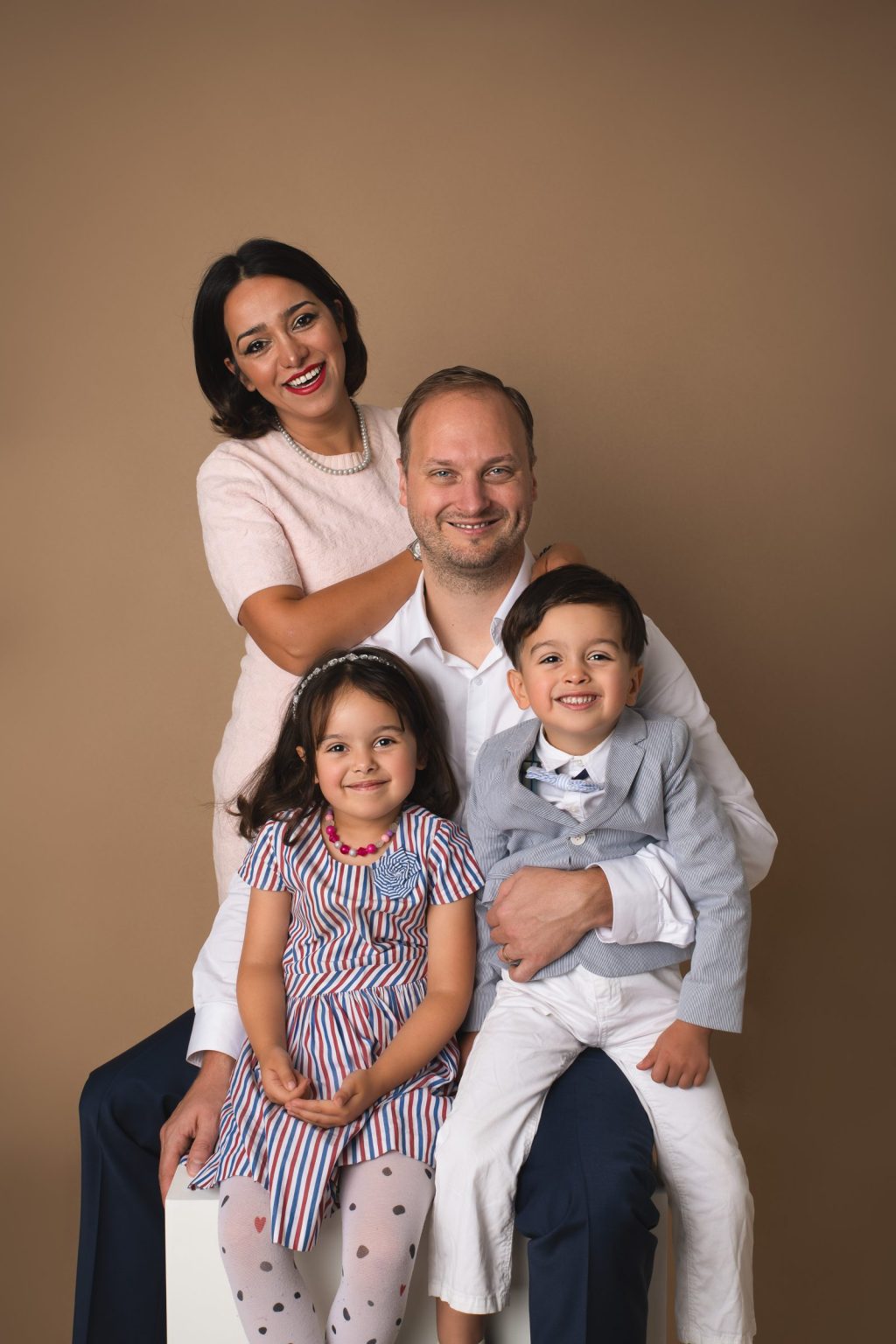 Parents et leurs deux enfants r&eacute;unis au studio sur fond beige &ndash; s&eacute;ance photo famille &agrave; Tournai