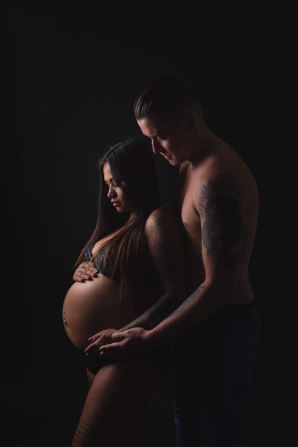 Futurs parents en clair-obscur, mains sur le ventre rond &ndash; s&eacute;ance photo grossesse &agrave; Tournai