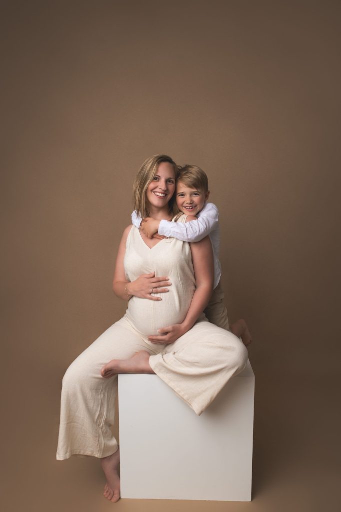 Future maman assise sur un cube blanc, sa fille dans les bras &ndash; s&eacute;ance photo grossesse &agrave; Tournai