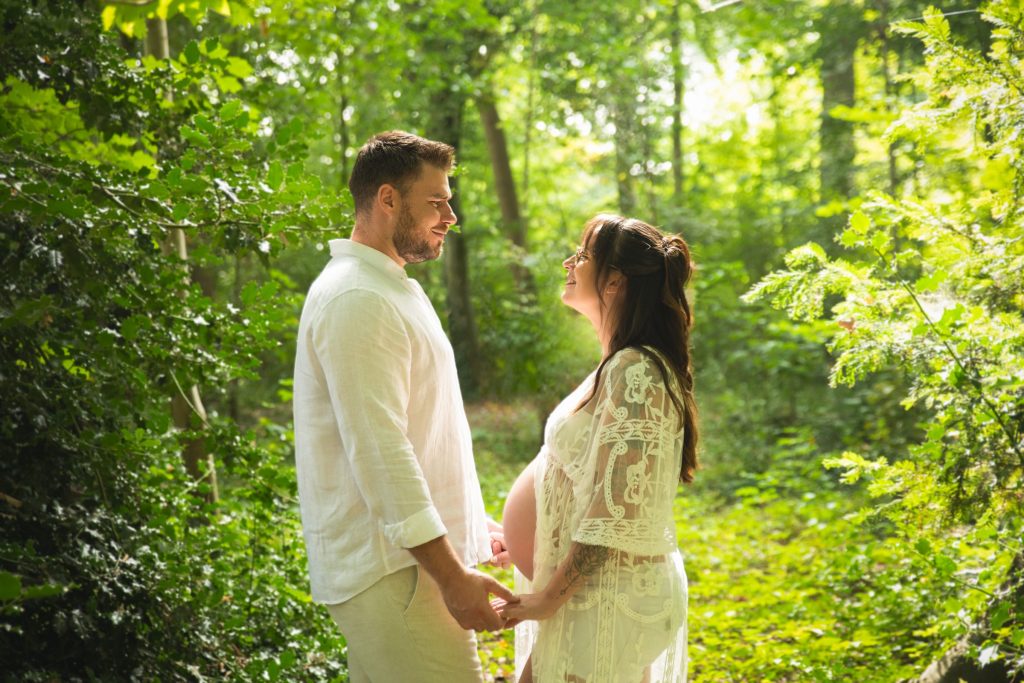 Futurs parents main dans la main dans une for&ecirc;t lumineuse &ndash; s&eacute;ance photo grossesse &agrave; Tournai