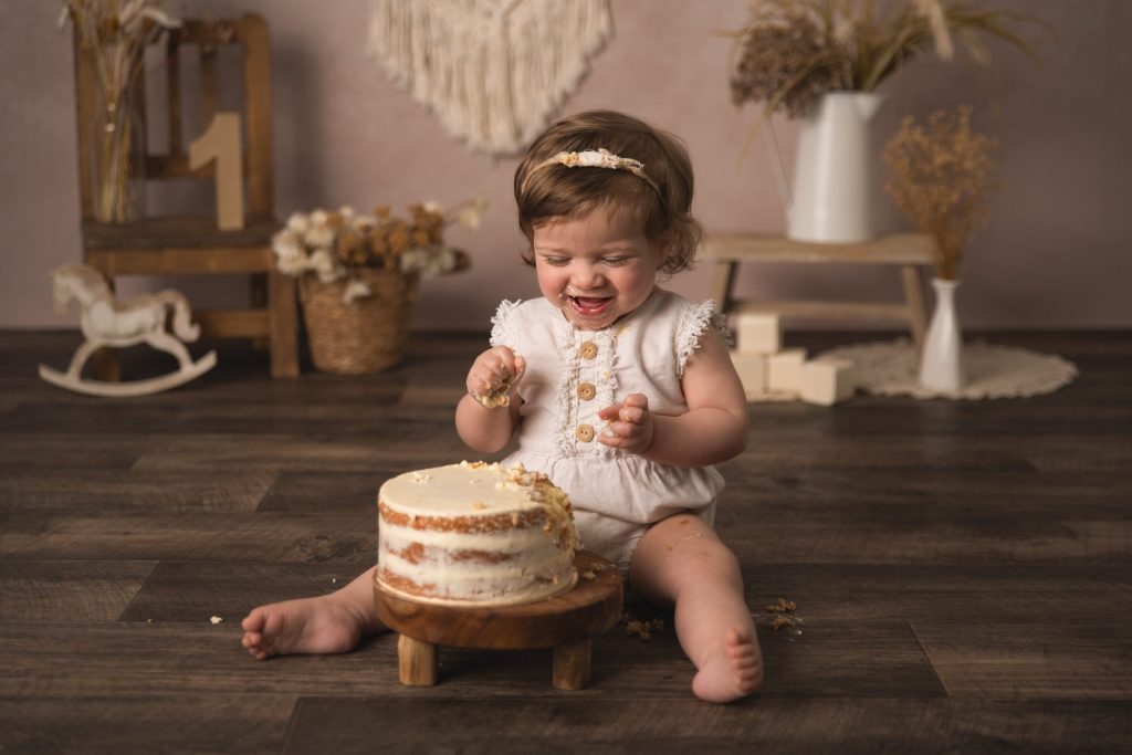 Smash the cake 8 Petite fille savourant son gâteau d’anniversaire, décor bohème – séance smash the cake à Tournai